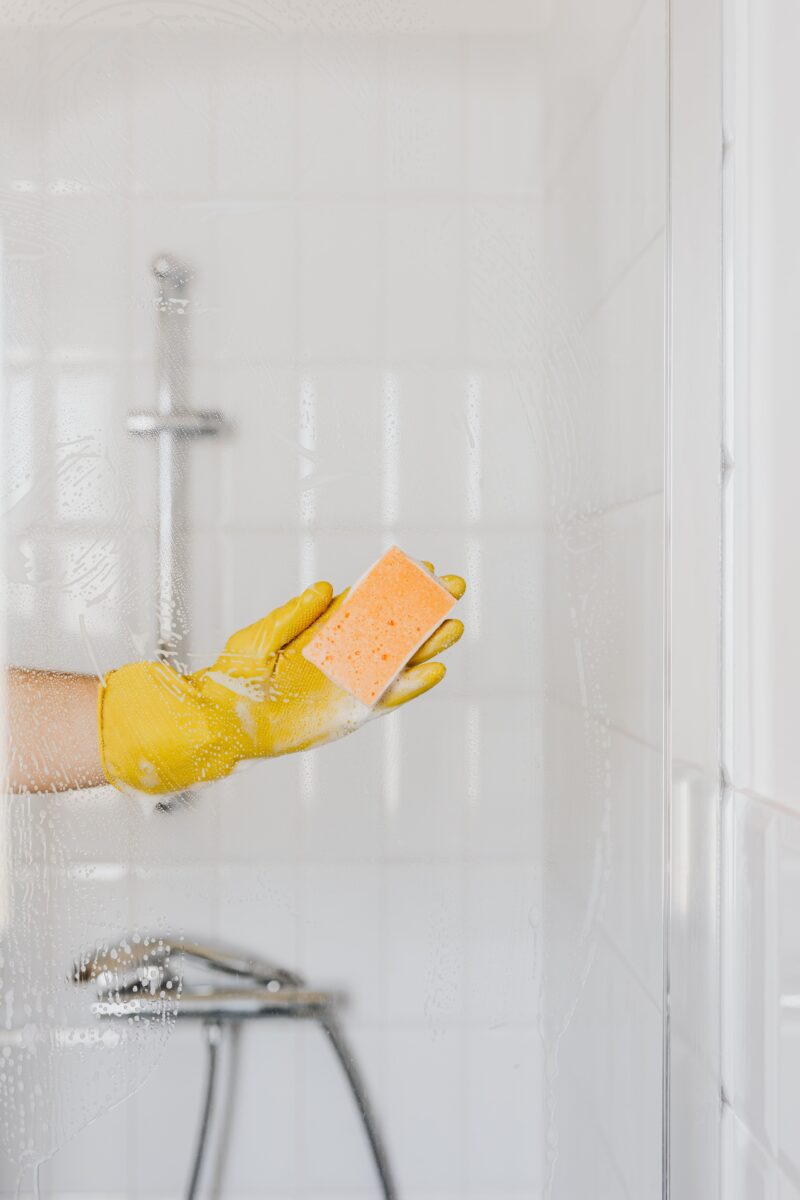 Person with glove cleaning shower glass door with sponge - Twin City Glass